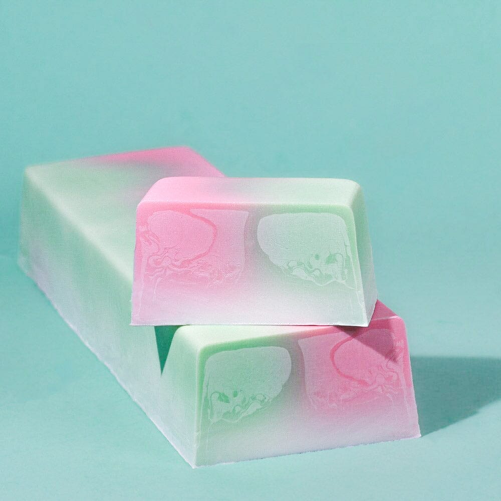 Blumenmaedchen PFLANZLICHE SEIFE Kirschblüte, Ein Seifenblock und ein frisch abgeschnittenes Seifenstück mit leuchtenden Farben. Pink, Grün, Weiss