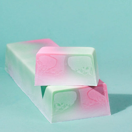 Blumenmaedchen PFLANZLICHE SEIFE Kirschblüte, Ein Seifenblock und ein frisch abgeschnittenes Seifenstück mit leuchtenden Farben. Pink, Grün, Weiss